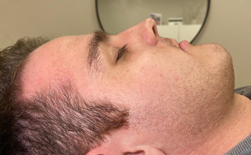 Close-up of a person wearing a gray beanie and beige shirt, looking downwards.