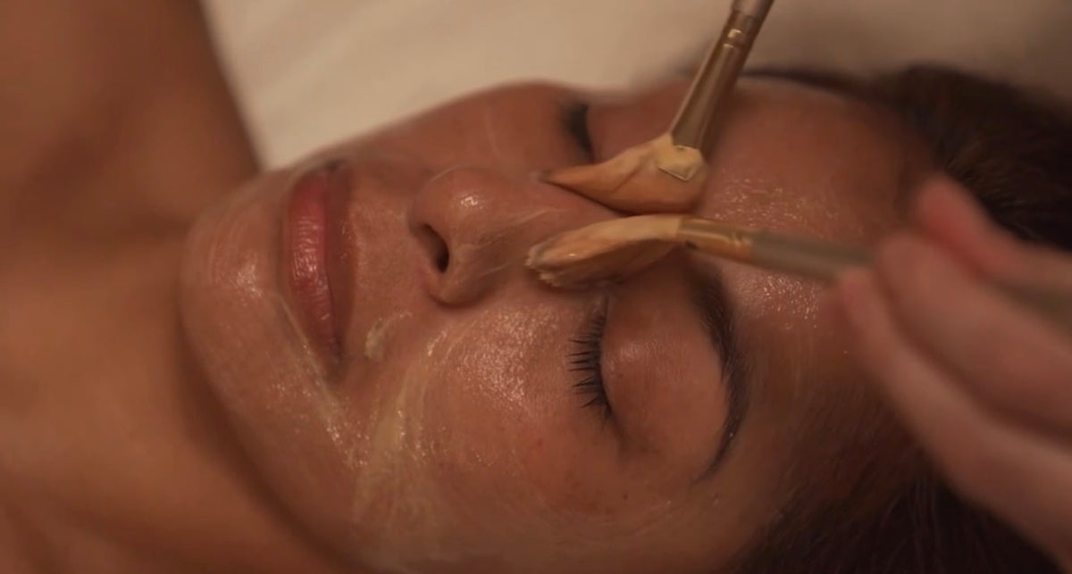 Client at Skin Chateau receiving a mask application with two mask brushes